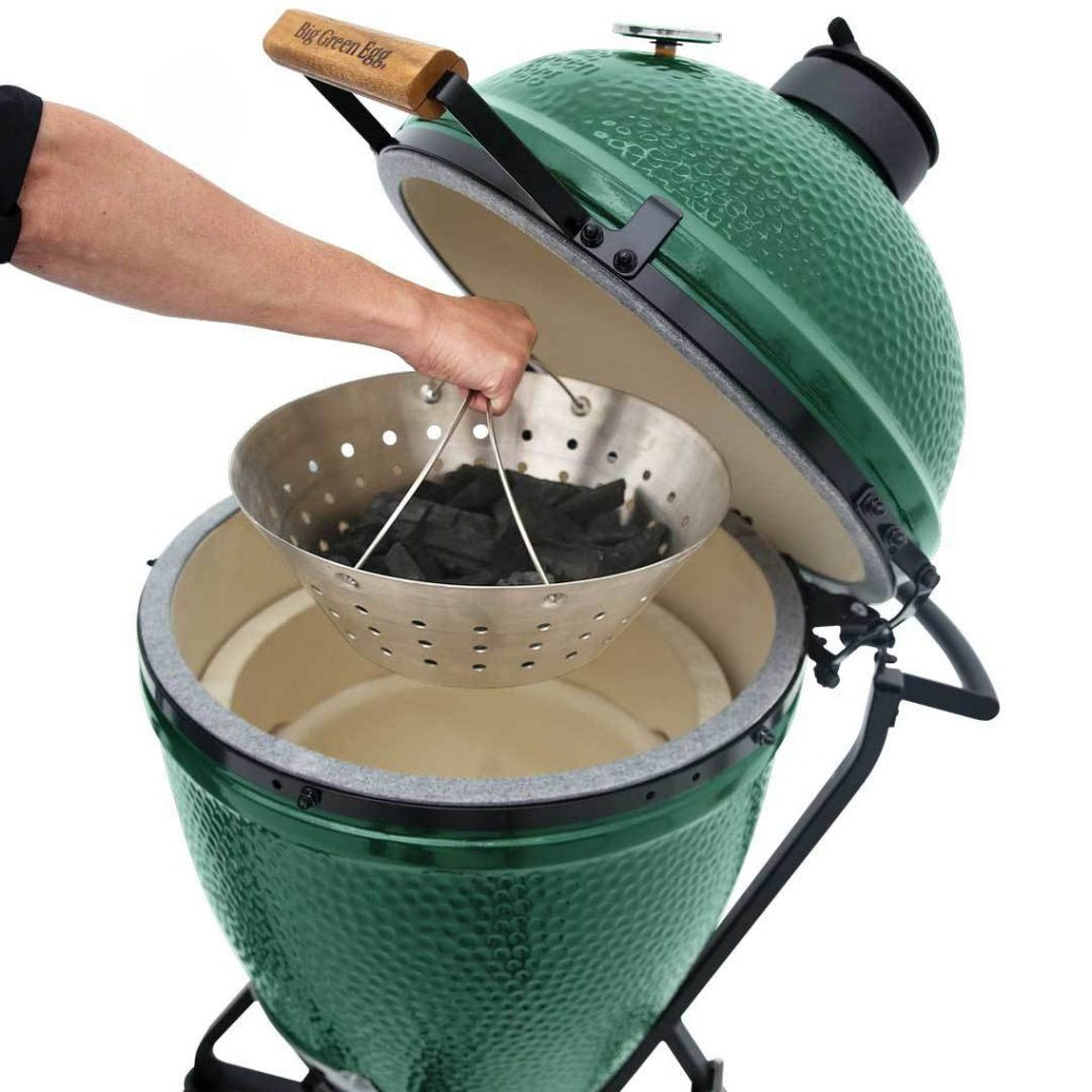 Person lifting a Big Green Egg fire bowl, charcoal basket, by the handles out of a Big Green EGG.